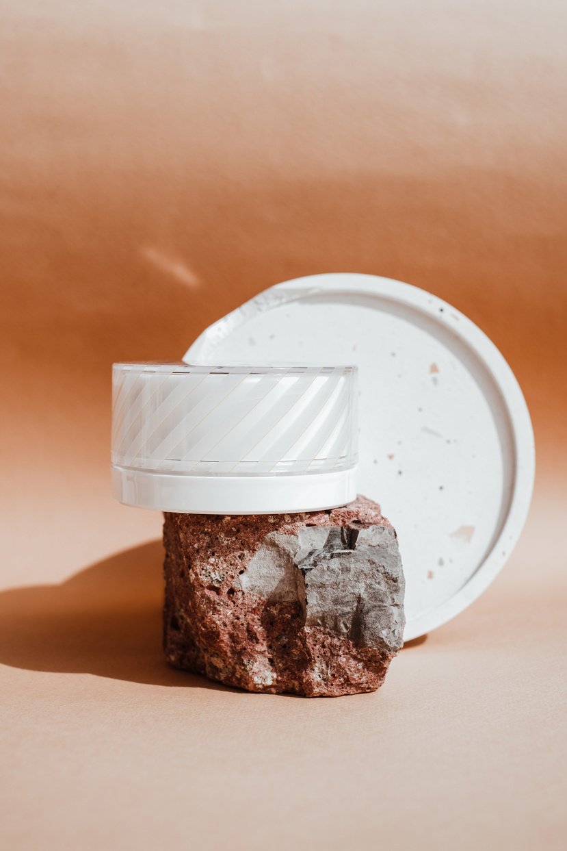 White Cosmetic Container on a Rock on Brown Background